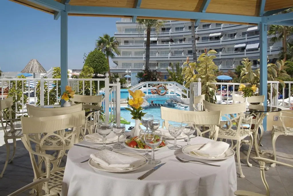 Une table dressée avec une salade fraîche en extérieur, face à une piscine et un bâtiment.