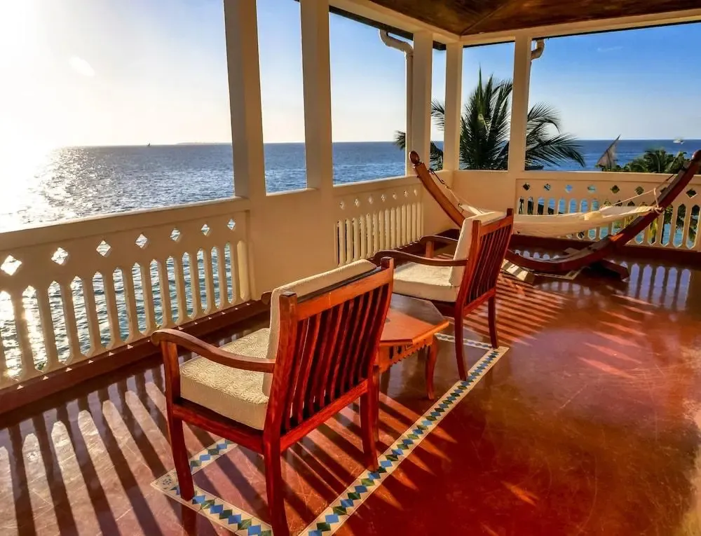 Terrasse ombragée avec mobilier en bois donnant sur la mer.