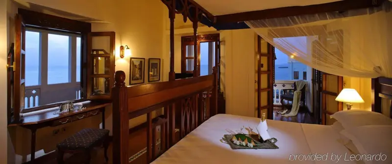 Une chambre lumineuse avec un grand lit à baldaquin et vue sur la mer.