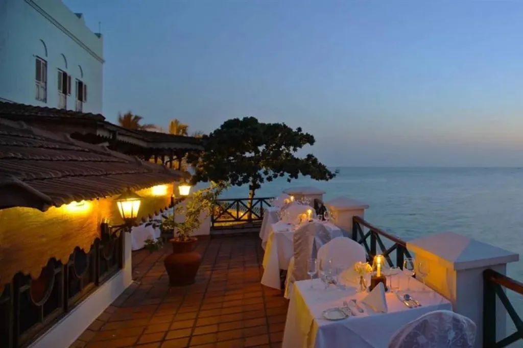 Tables dressées en terrasse avec vue sur la mer au crépuscule.