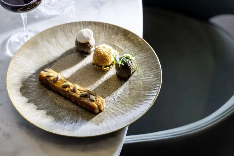 Assiette raffinée présentant un dessert composé de plusieurs éléments texturés et colorés.