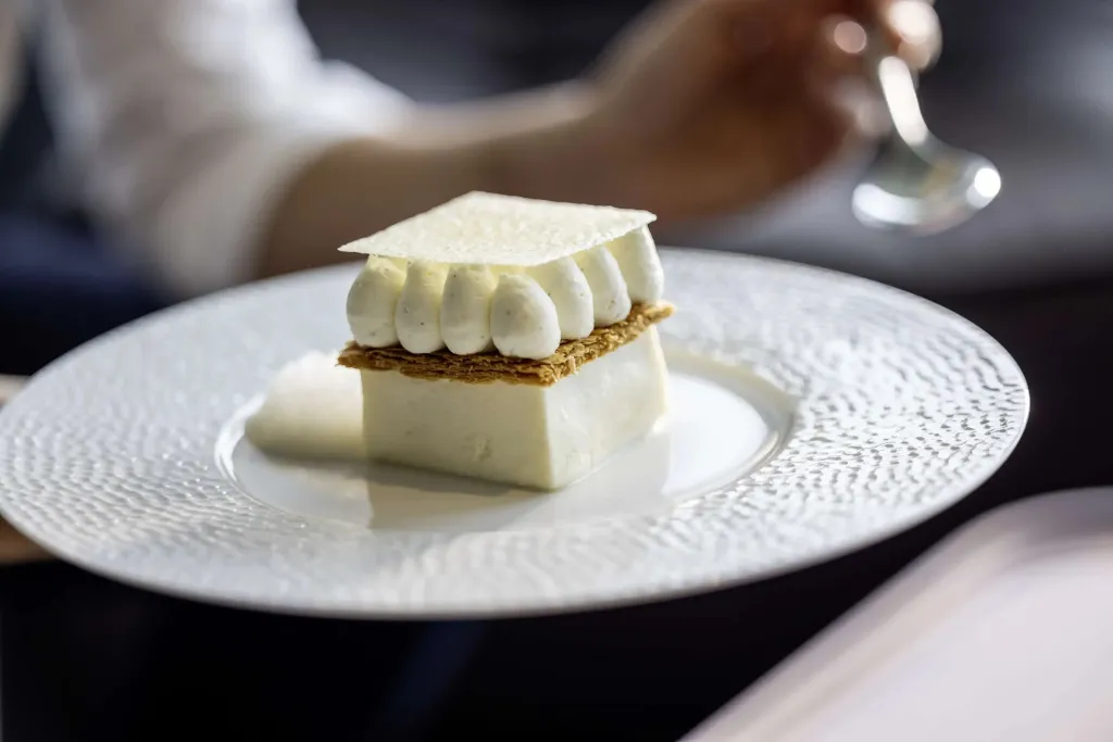 Un dessert raffiné est présenté sur une assiette blanche texturée.