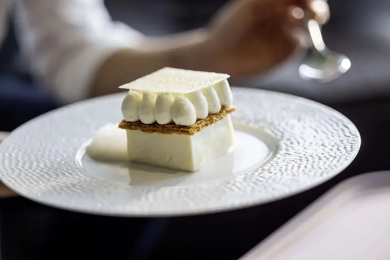 Un dessert raffiné est présenté sur une assiette blanche texturée.