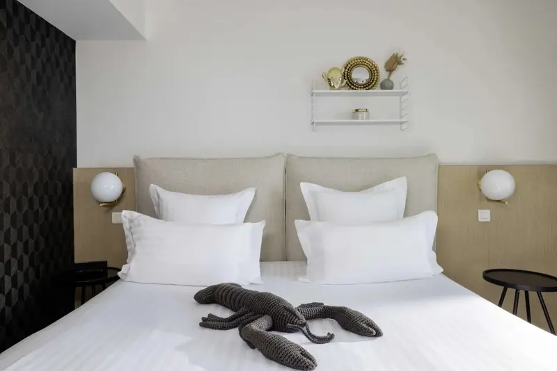 Un lit double est soigneusement fait avec des oreillers moelleux dans une chambre lumineuse.