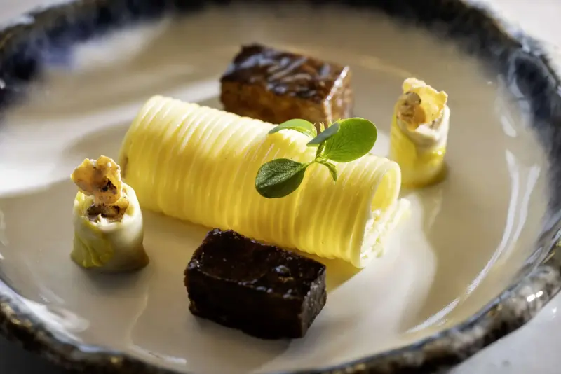 Présentation raffinée d'un dessert aux textures variées sur une assiette texturée.
