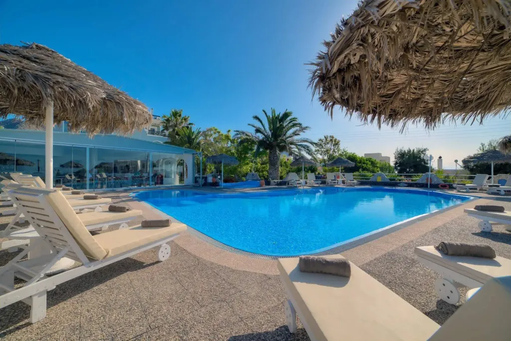 Transats et parasols ombragent une piscine rectangulaire bordée d'une terrasse.