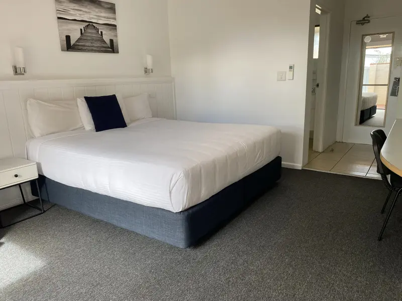 Une chambre lumineuse avec un grand lit recouvert de linge blanc.