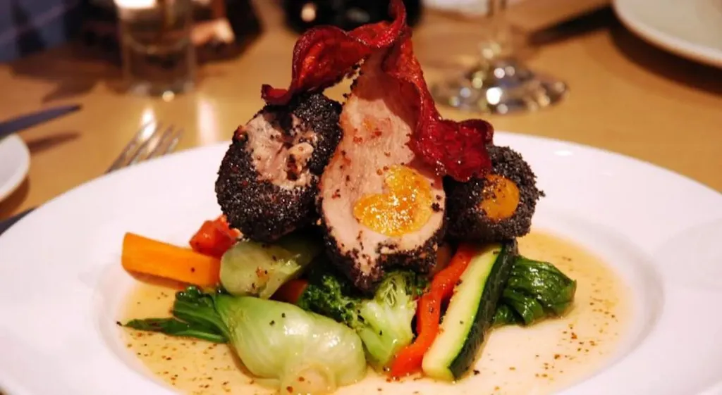 Assiette raffinée avec une préparation à base de viande, de légumes et d'une sauce crémeuse.