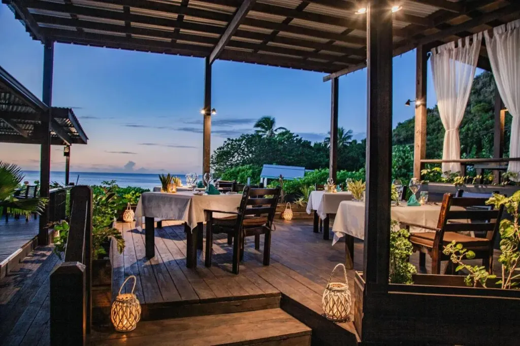 Terrasse de restaurant avec tables dressées face à la mer au crépuscule.