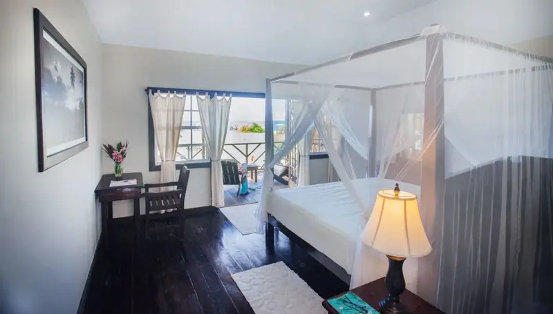 Une chambre lumineuse avec un lit à baldaquin donnant sur une vue sur la mer.