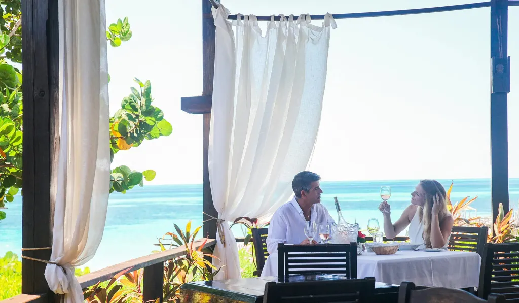 Un couple déjeune à une table en plein air avec vue sur la mer.
