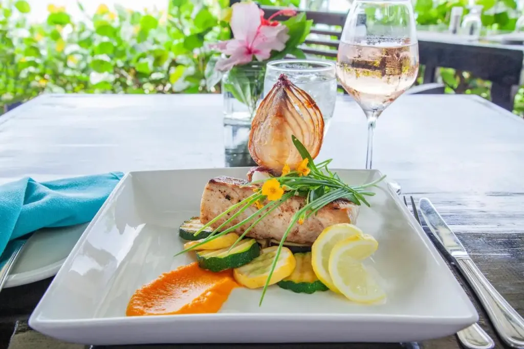 Un plat de poisson grillé est présenté sur une table en extérieur.