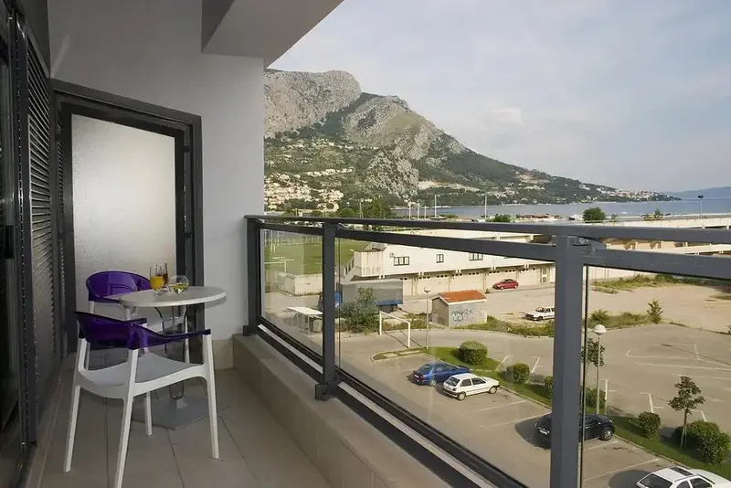Une terrasse avec une table et des chaises offre une vue sur la mer et les montagnes.