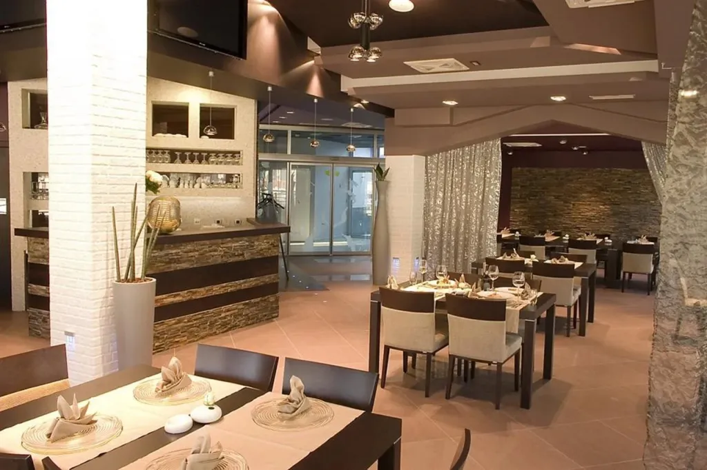 Une salle de restaurant lumineuse avec des tables dressées et un comptoir de bar.