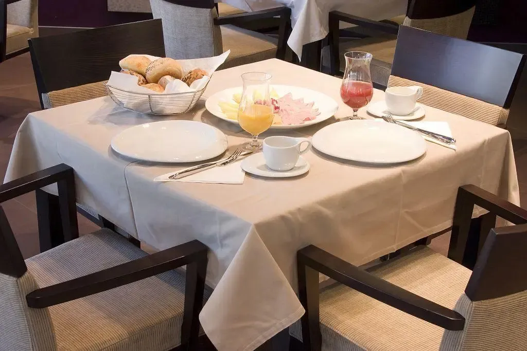 Une table est dressée pour le petit-déjeuner avec des viennoiseries, des fruits et des boissons.