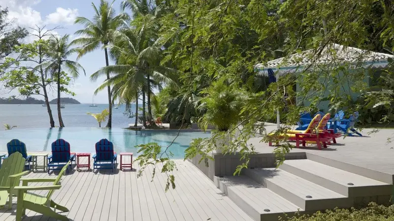 Terrasse en bois avec chaises longues colorées au bord d'une piscine à débordement.