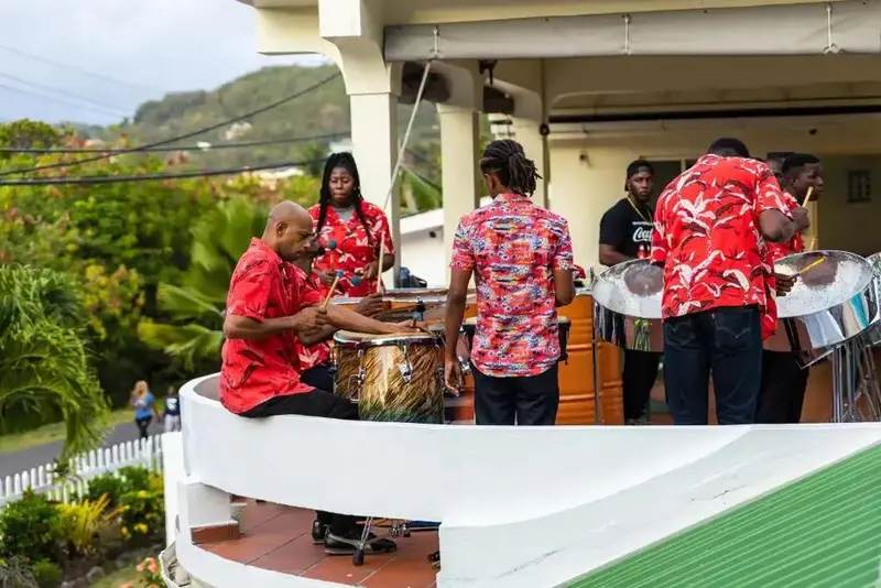Un groupe de musiciens joue de la percussion sur une terrasse ensoleillée.