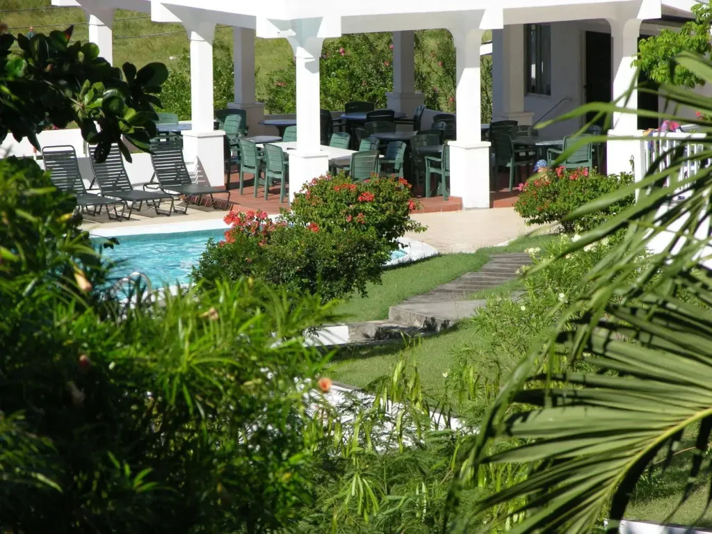 Une piscine bordée de chaises longues et d'une terrasse ombragée avec des tables et des chaises.
