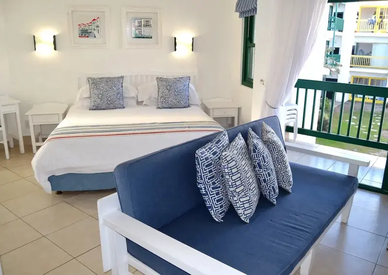 Une chambre lumineuse avec un lit double et un coin salon.