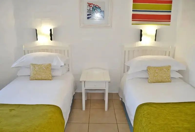 Une chambre lumineuse avec deux lits simples et une décoration sobre.