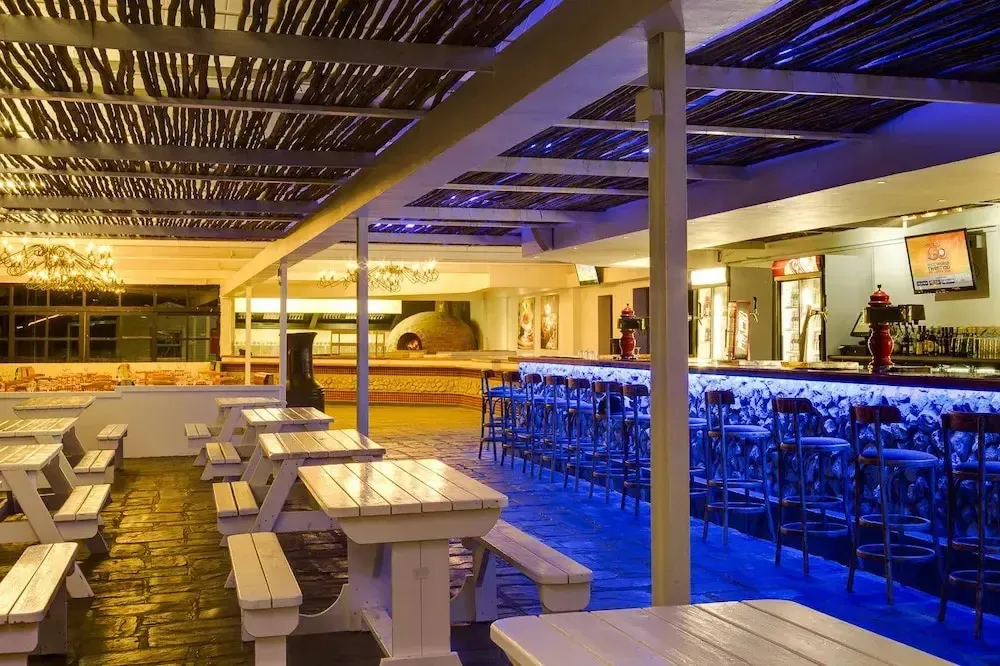 Terrasse lumineuse avec tables et un bar éclairé en bleu.