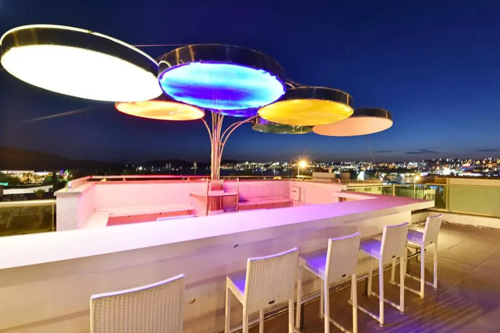 Un bar sur le toit illuminé surplombe une ville nocturne.