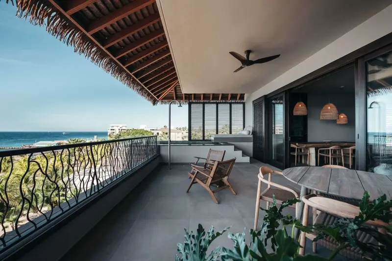Terrasse aménagée avec mobilier en bois et vue sur la mer.