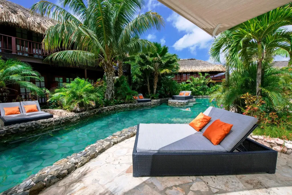 Transats confortables au bord d'un cours d'eau turquoise dans un jardin tropical.