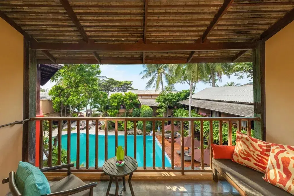 Terrasse ombragée donnant sur une piscine et une végétation luxuriante.