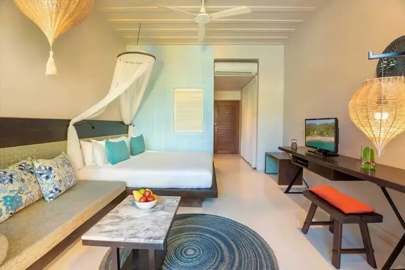Une chambre lumineuse avec un lit à baldaquin et un coin salon.