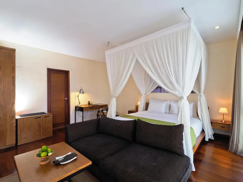 Une chambre lumineuse avec un lit à baldaquin et un coin salon.