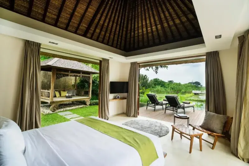Une chambre lumineuse s'ouvre sur une terrasse et un jardin tropical.