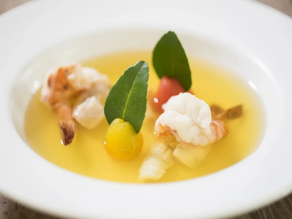 Une assiette de fruits de mer et de légumes dans un bouillon clair.