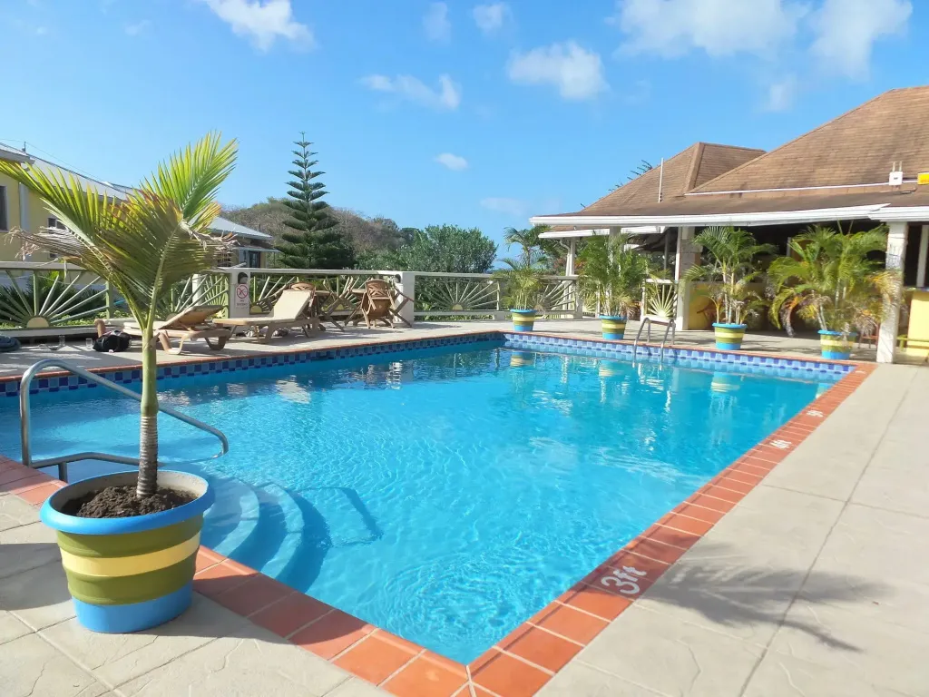 Une piscine rectangulaire entourée d'une terrasse ensoleillée avec des transats.