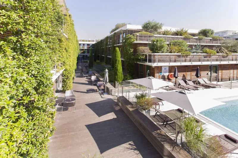 Terrasse en bois avec transats et piscine ensoleillée.
