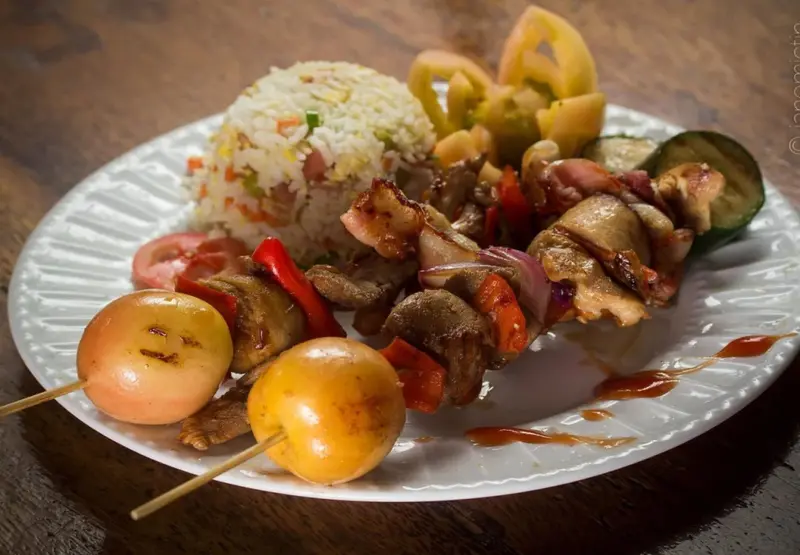 Assiette garnie de brochettes de viande, de riz et de légumes.