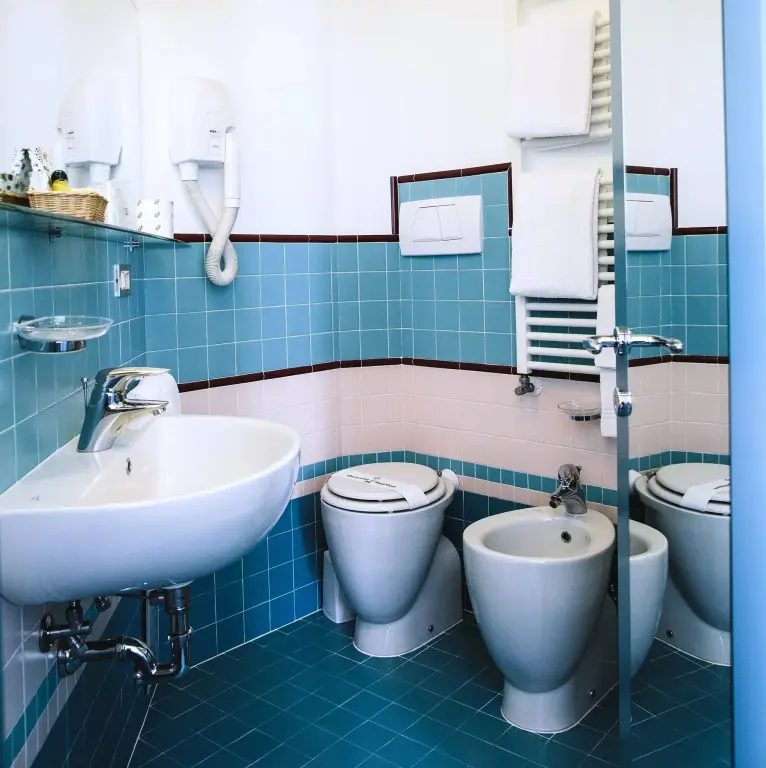 Une salle de bain claire avec des sanitaires blancs et des carreaux turquoise.