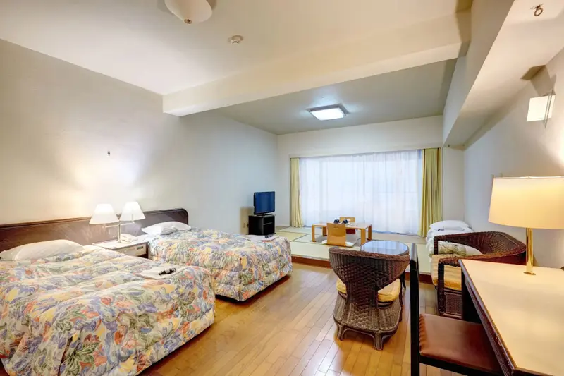 Une chambre lumineuse avec deux lits et un coin repas près de la fenêtre.
