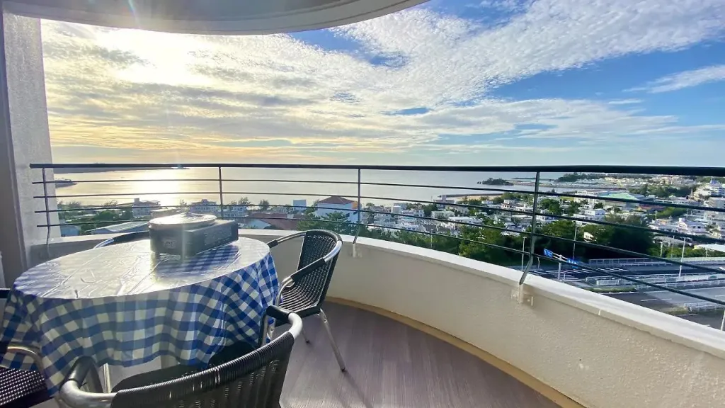 Une terrasse avec une table recouverte d'une nappe à carreaux offre une vue sur la mer et la ville.