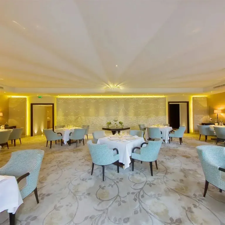 Une salle lumineuse avec des tables dressées pour un repas.