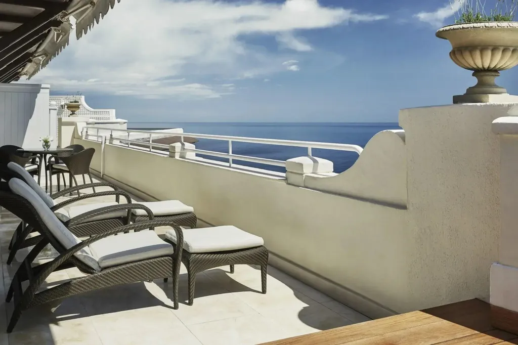 Transats et table basse sur une terrasse offrant une vue sur la mer.