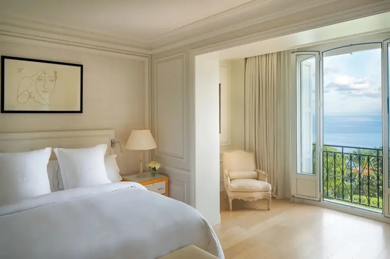 Une chambre lumineuse s'ouvre sur un balcon avec vue sur la mer.