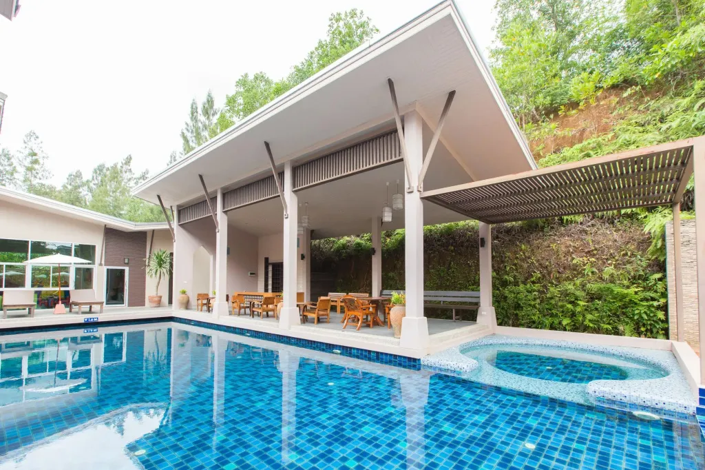 Une piscine rectangulaire bleue avec un espace détente ombragé à côté.