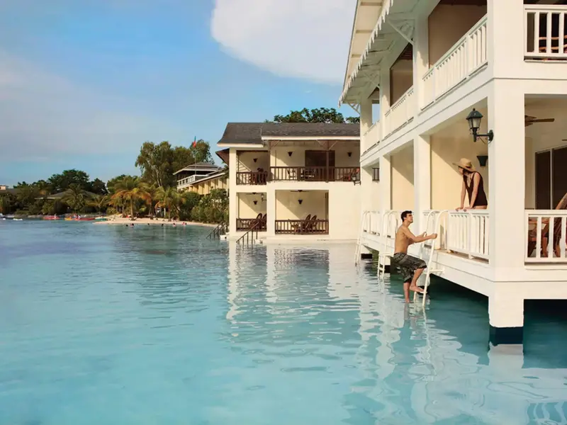 Des bungalows blancs sur pilotis surplombent une eau turquoise et calme.