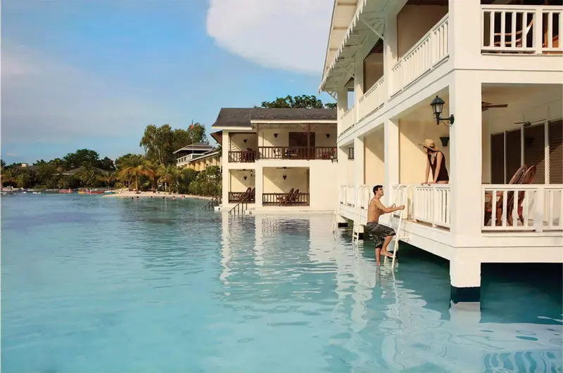 Des bungalows blancs sur pilotis s'avancent dans une eau turquoise.