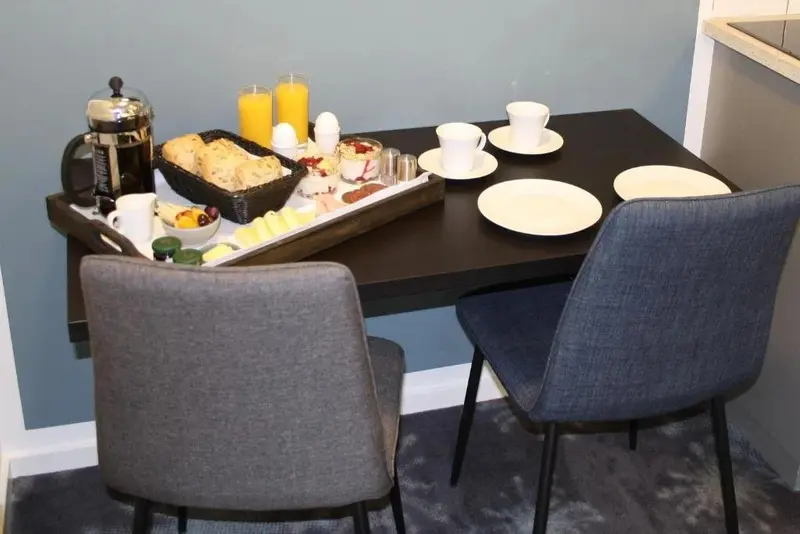 Une table est servie pour le petit-déjeuner avec des viennoiseries, des fruits et des boissons.