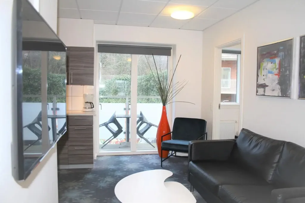 Un espace de vie lumineux avec un canapé, une table basse et un accès à une terrasse.
