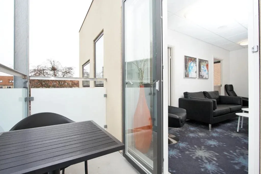 Une table et des chaises se trouvent sur une terrasse ouverte sur un salon.