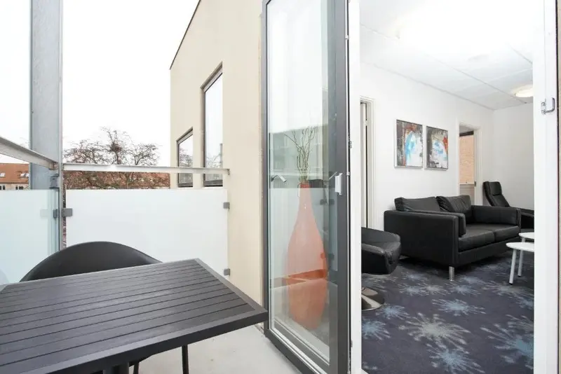 Une table et des chaises se trouvent sur une terrasse ouverte sur un salon.
