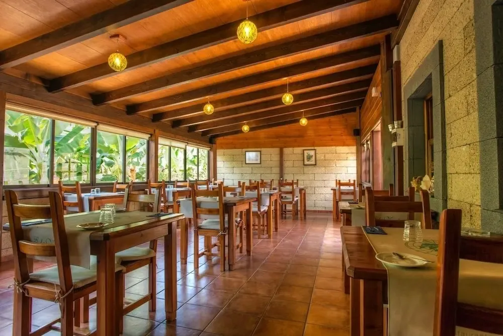 Une salle de restaurant lumineuse avec des tables en bois et des suspensions décoratives.
